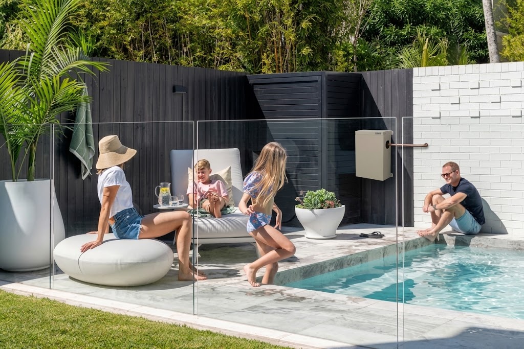 A family at home in the backyard, with a whole home water filtration system mounted on the wall