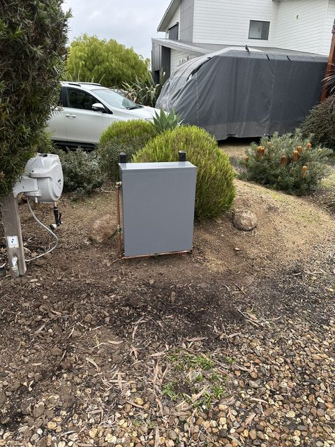 Finished water filtration installation inside a grey weatherproof enclosure