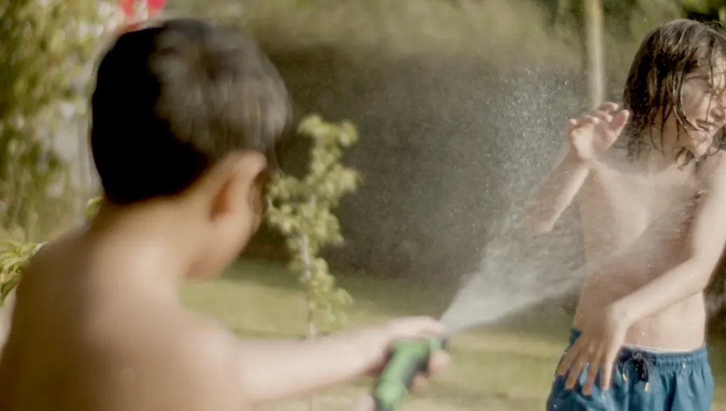 Children playing with a running garden hose outside a Melbourne home